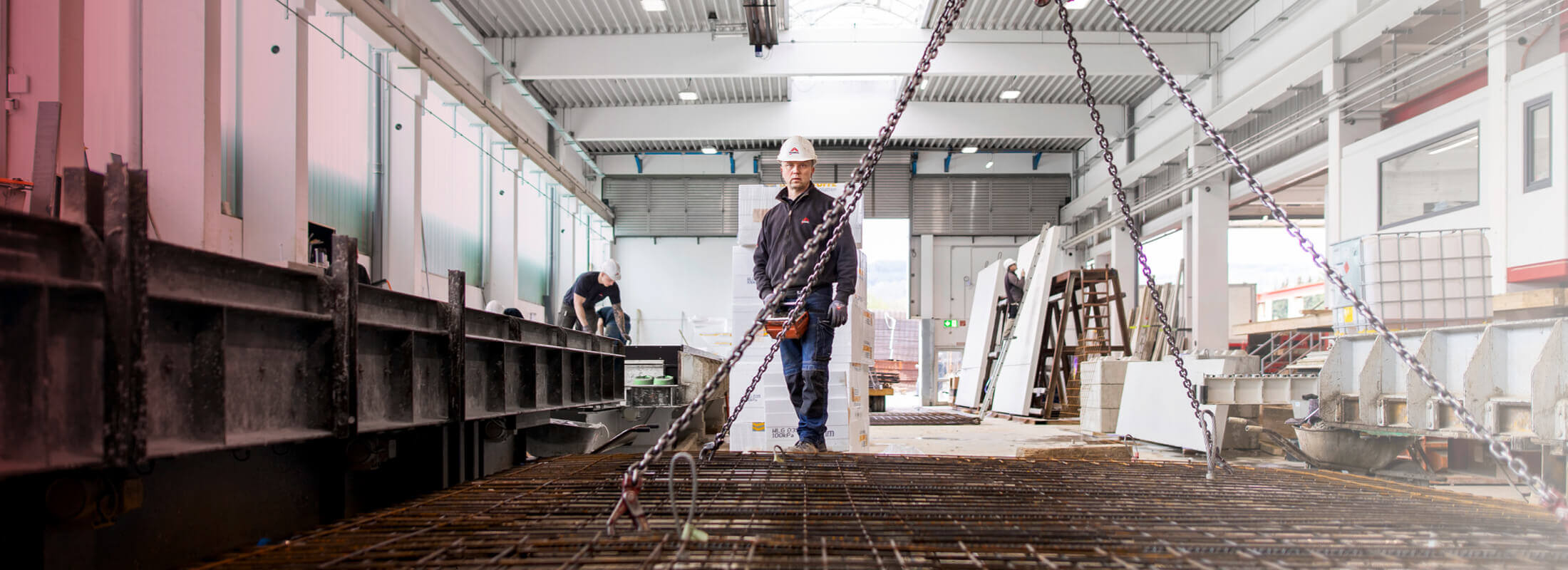 Ein Runkelmitarbeiter vor einem Metallgitter, das an Ketten aufgehangen ist